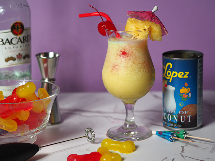 Pina colada drink sitting on a table in front of a turquoise background